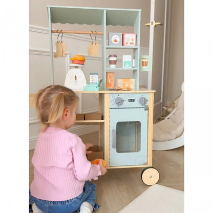 Child reaching toward mint green wooden play kitchen with white oven door