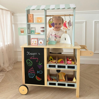 Toddler interacting with food truck stand, chalkboard showing colorful food drawings