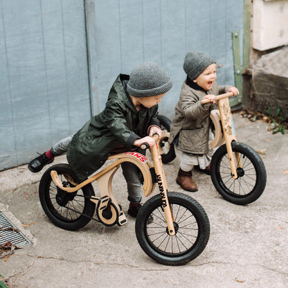 Two children riding leg&go balance bikes with pedals on urban street
