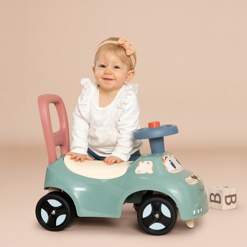 Toddler riding turquoise push-along car with removable pink backrest and blue horn