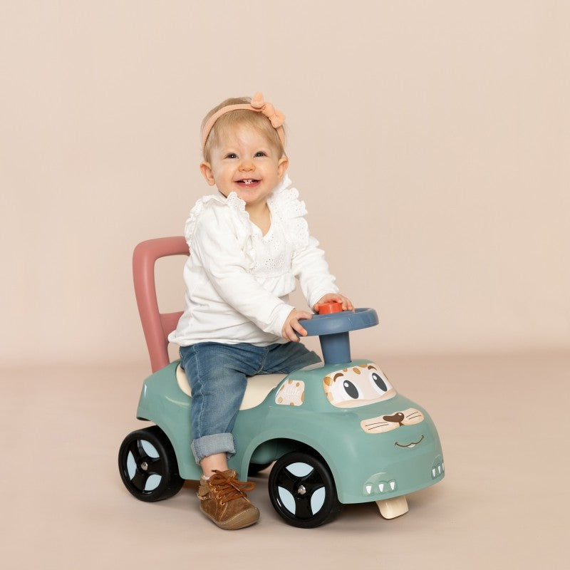 Seated toddler playing with blue horn on turquoise pastel ride-on toy