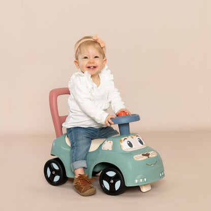 Seated toddler playing with blue horn on turquoise pastel ride-on toy