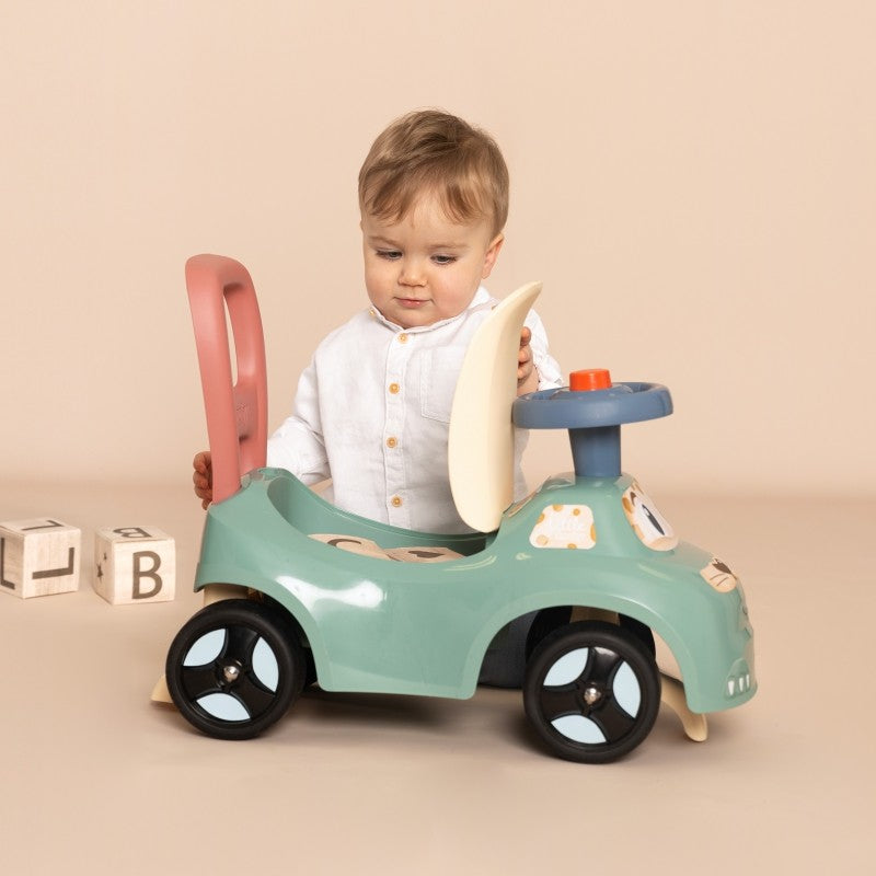 Toddler exploring cream-colored seat compartment on turquoise ride-on pusher