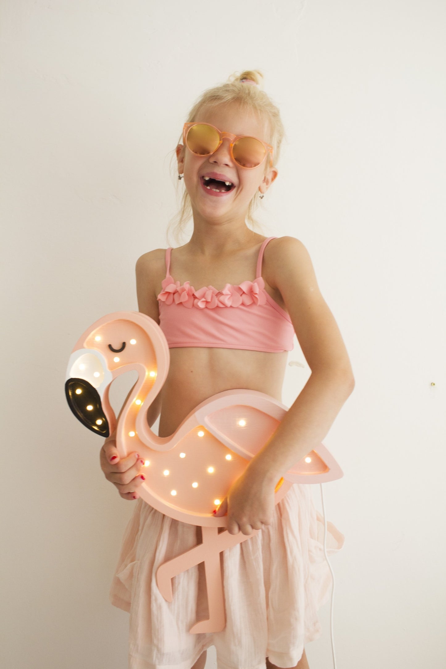 Girl posing with glowing pink flamingo LED lamp showing warm light details and pinewood construction