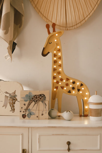 Illuminated giraffe lamp on dresser with warm white LEDs near woven heart wall decal