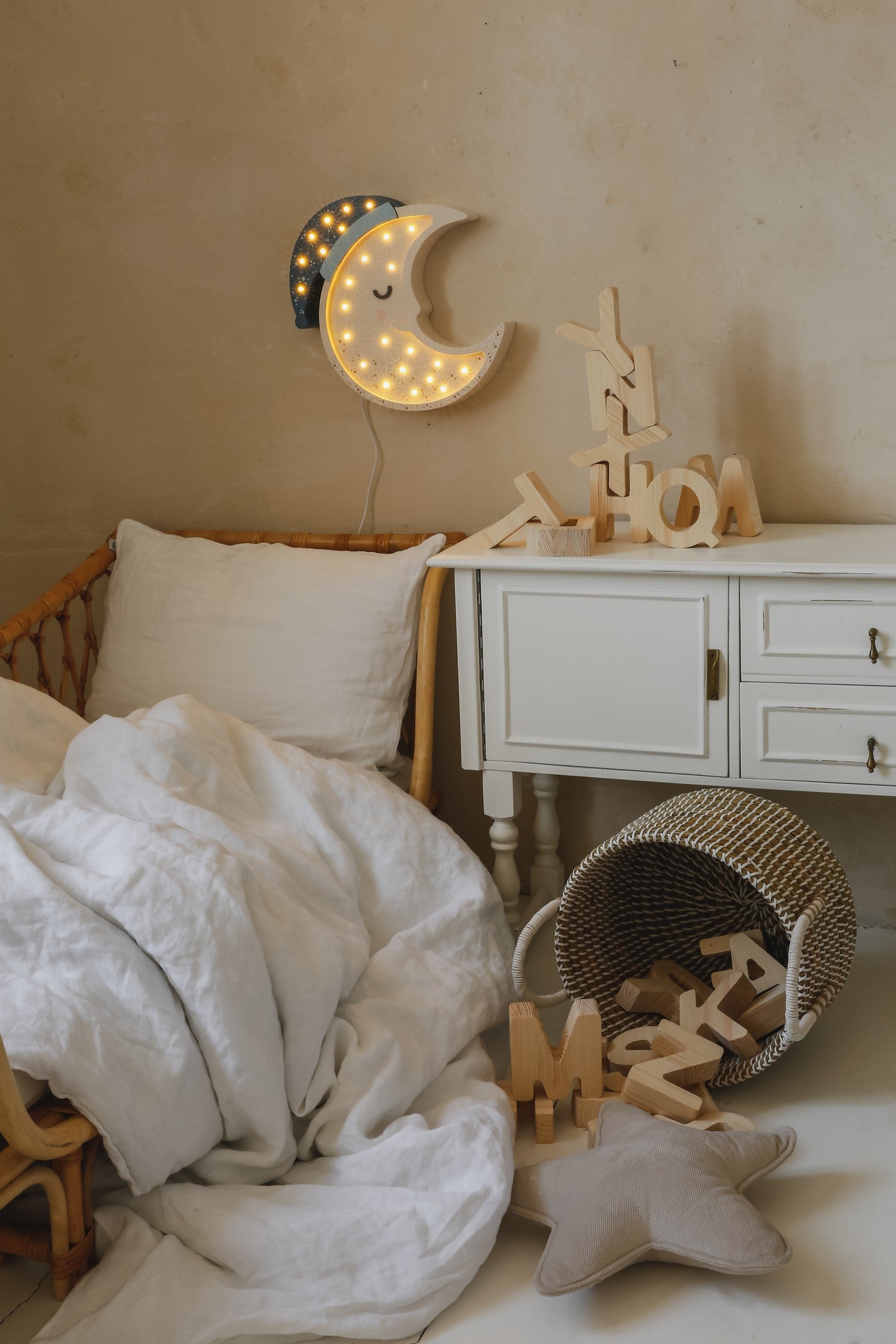 Moon lamp lit up with warm white LEDs mounted on wall above child's crib with bedside furniture