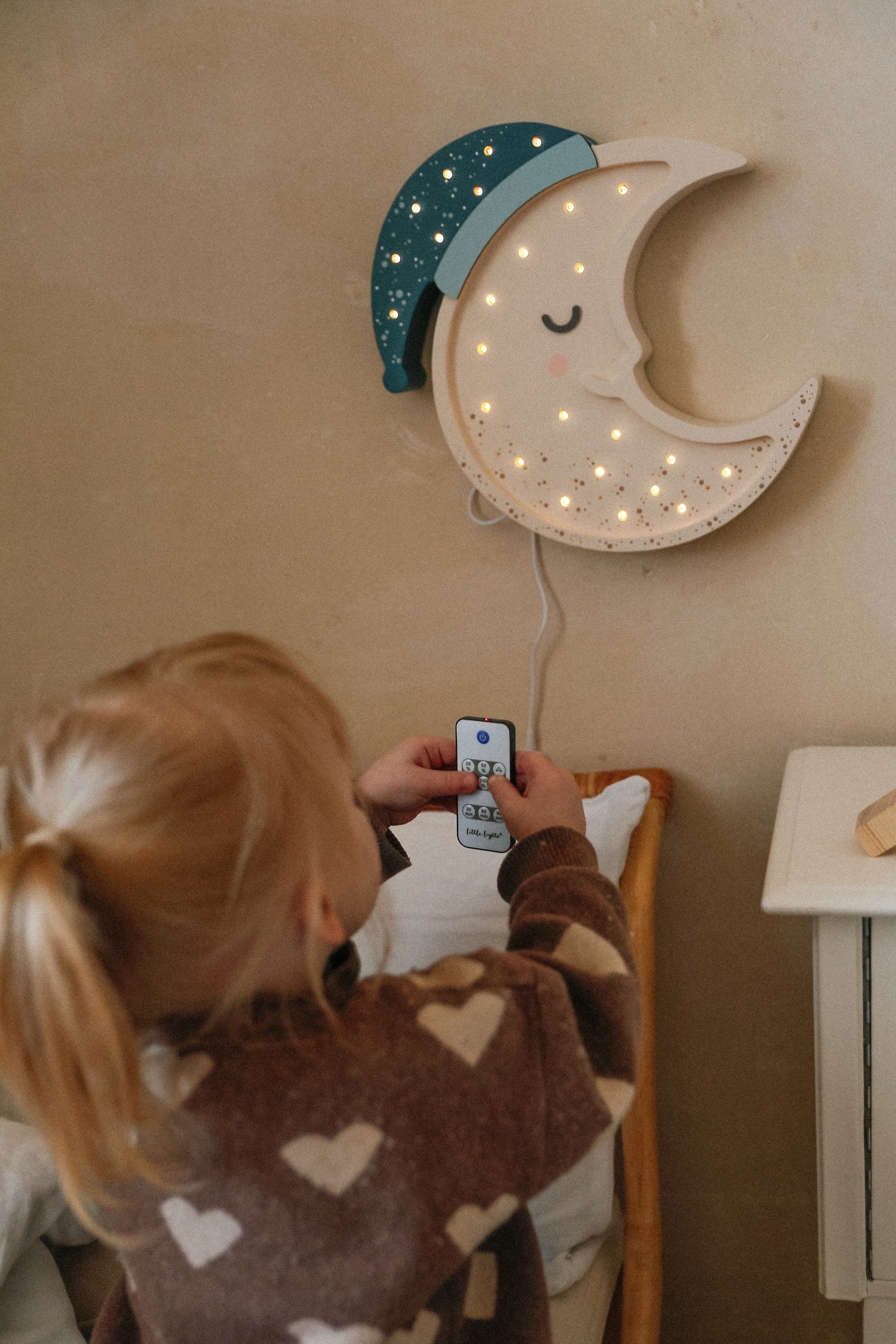 Child using remote control to adjust moon lamp dimmer and timer features