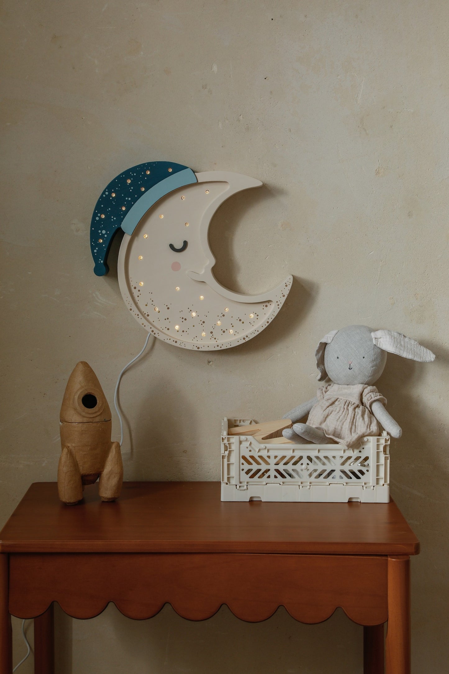 Moon lamp with illuminated LED lights displayed on shelf above wooden dresser with toys