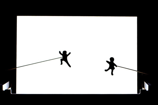 Two stick figures playing on a bright white light board panel