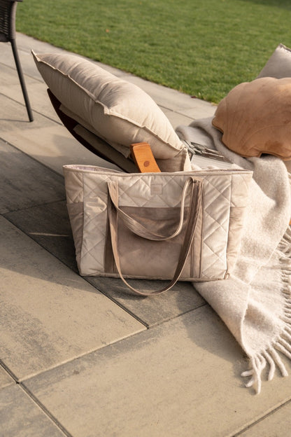 Beige velvet maternity bag filled with pillows and blanket, styled on outdoor patio setting
