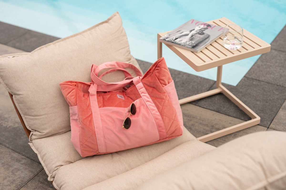 Candy pink velvet weekender bag styled on poolside lounge chair with casual setup