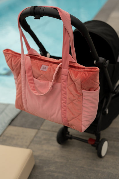 Candy pink quilted weekender bag attached to stroller with pink handles and outer pockets