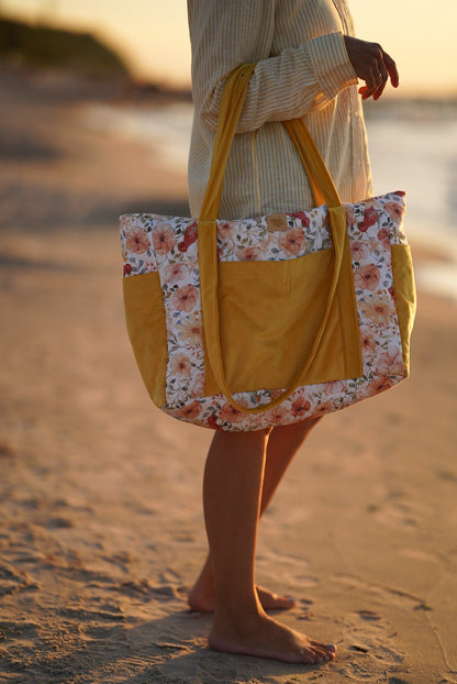 Woman with weekender bag on shoulder at beach, showing bag worn crossbody style