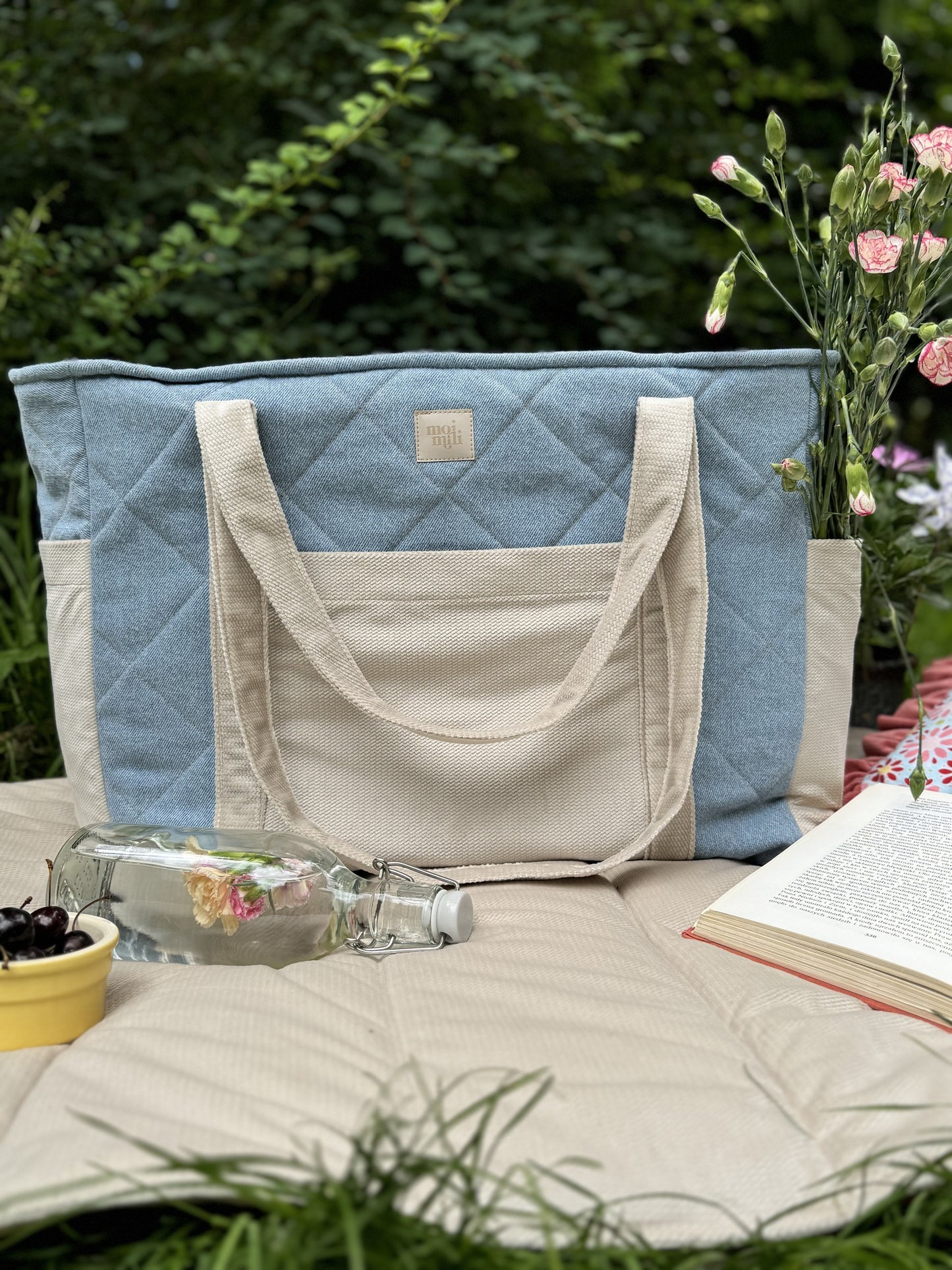 Jeans weekender bag displayed outdoors with cream handles and quilted velvet cotton exterior