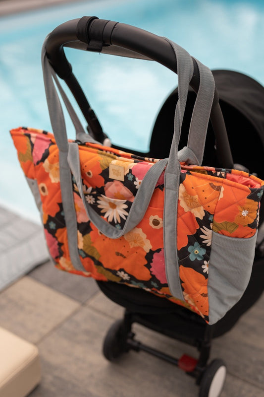 Floral weekender bag with colorful flower print hanging on stroller by poolside