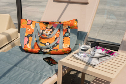 Picnic With Flowers weekender bag styled on lounge chair with accessories and phone