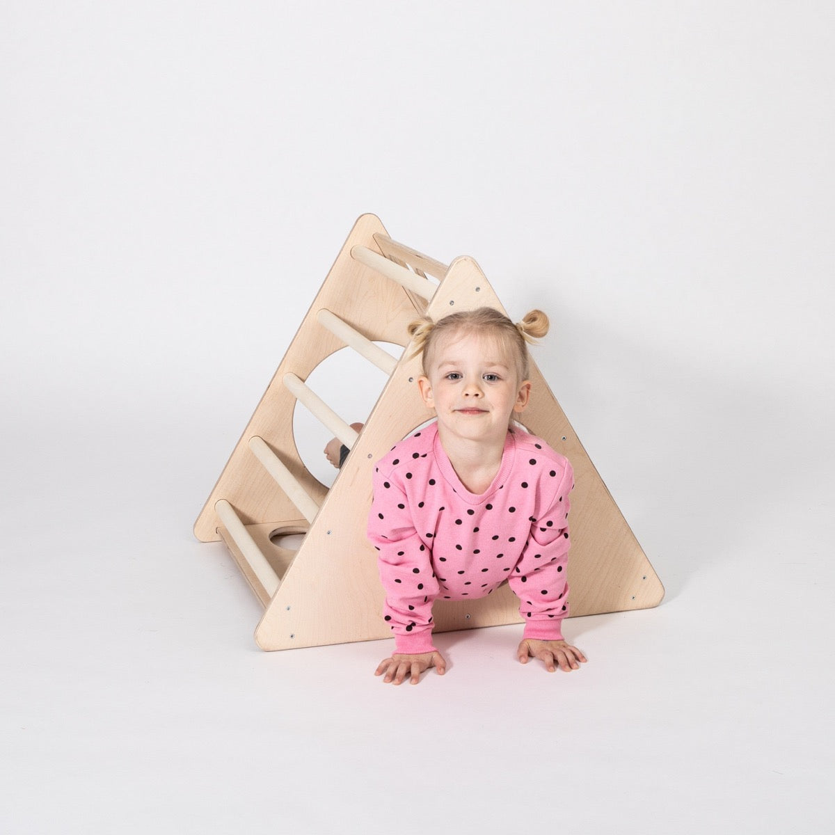 Young child crawling through opening of birch climbing triangle