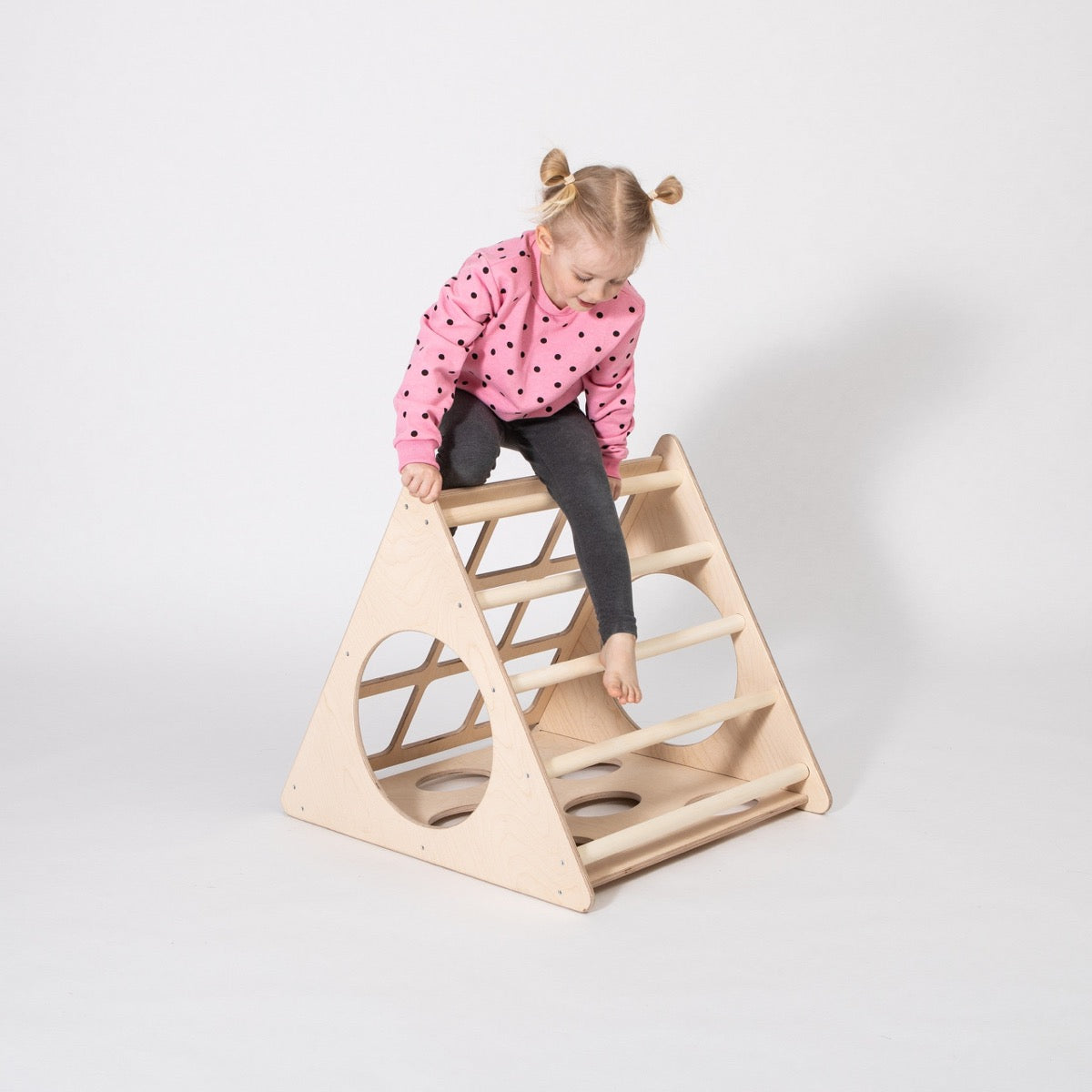 Child climbing up wooden triangle ladder with grip cutouts