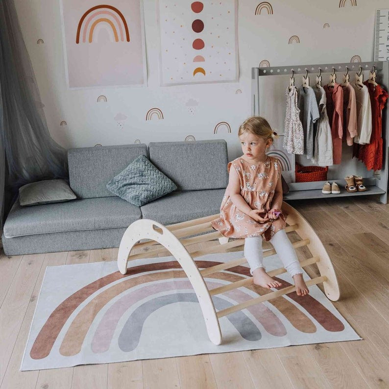 Child playing on birch wood climbing arch with ramp attachment in living room