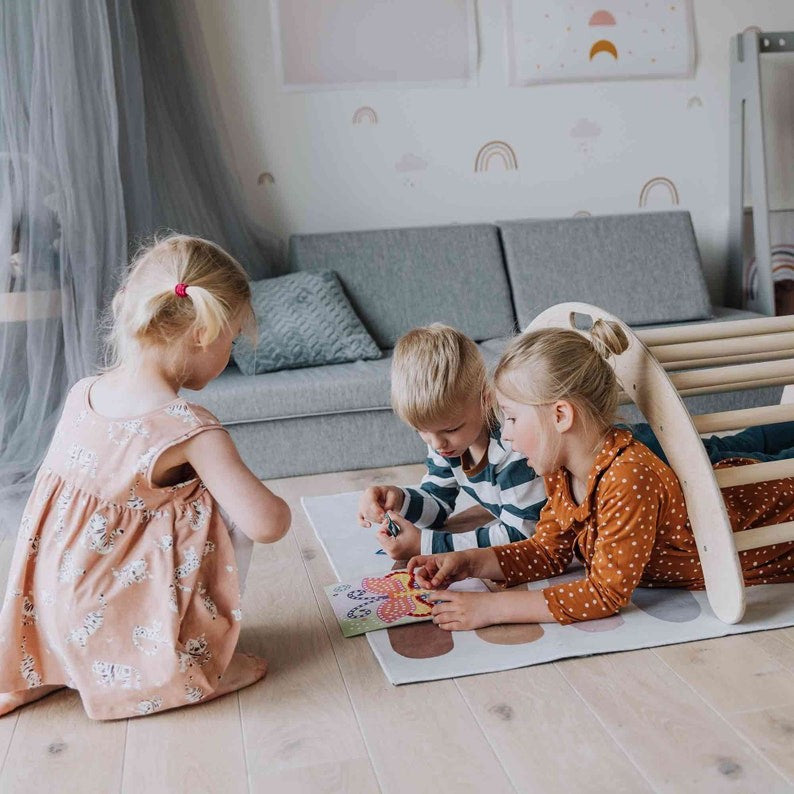 Three toddlers playing together on wooden climbing arch and balance board