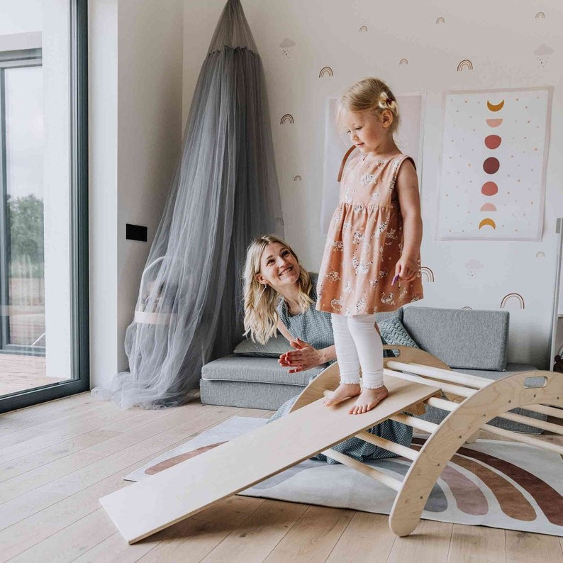 Two children using flipped arch as balance board with ramp extension nearby