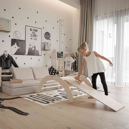 Child balancing on birch wood climbing arch with ramp in modern nursery room