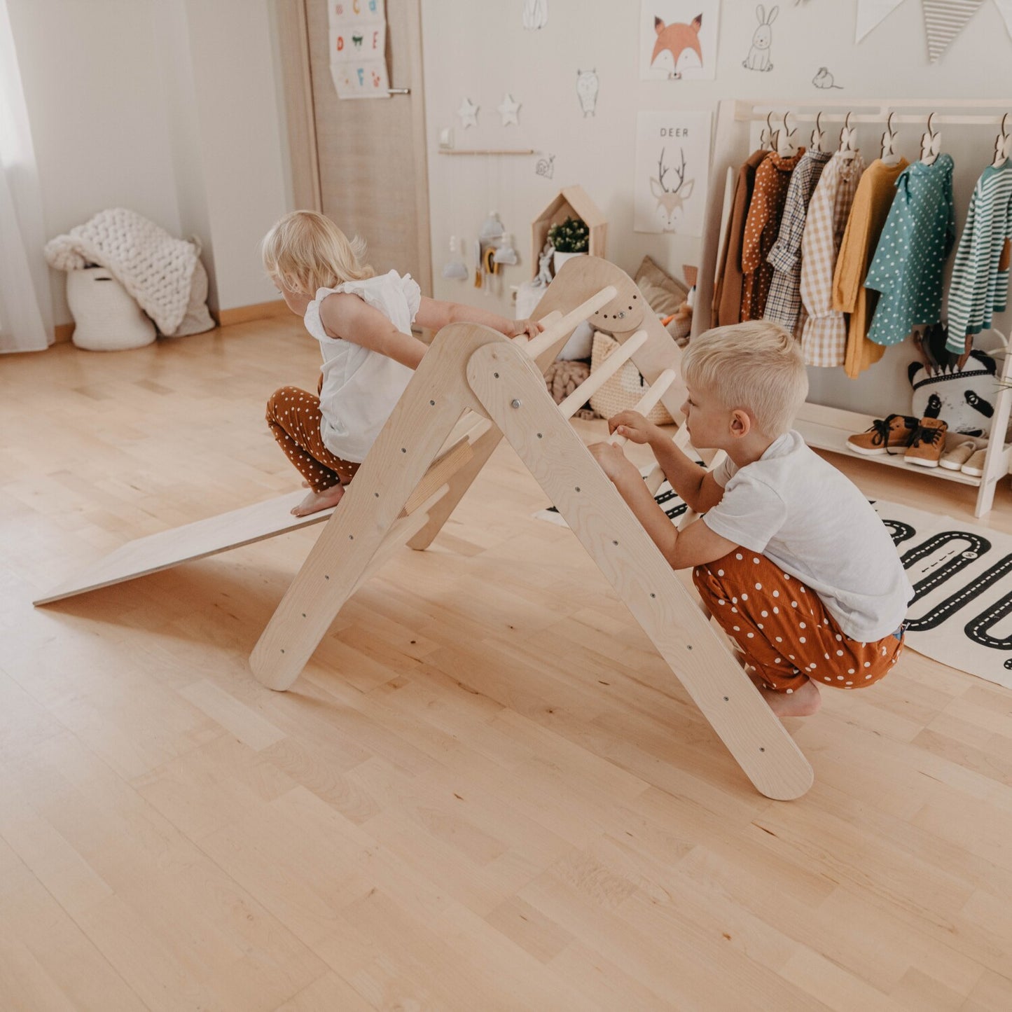 Two toddlers playing on the foldable climbing triangle in a Montessori room