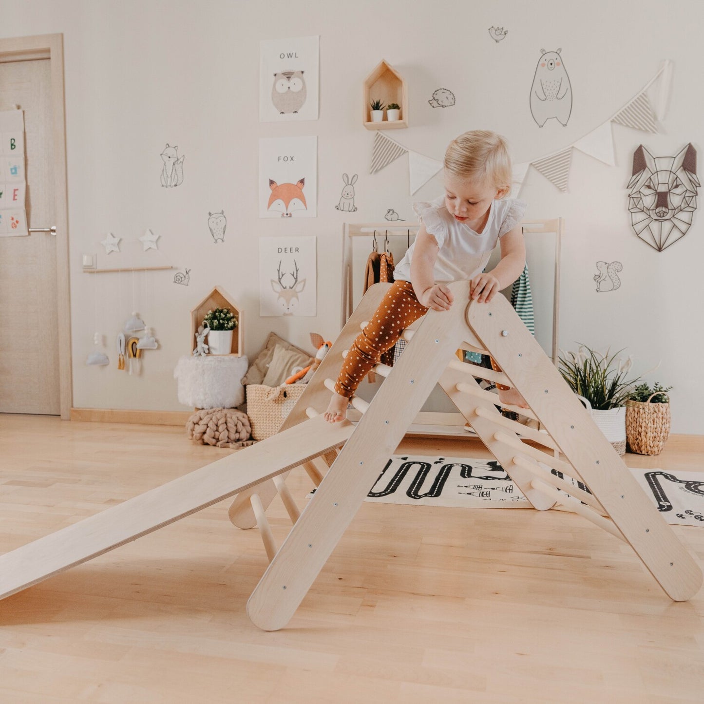 Young child sliding down the ramp of the climbing triangle during active play