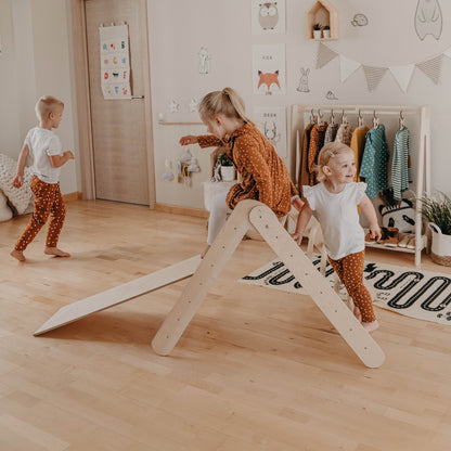 Multiple children playing together on the wooden climbing triangle with ramp