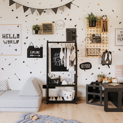 Black house-shaped clothing rack in scandinavian-style kids room with educational wall decor