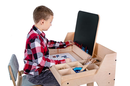 Child drawing on Luula art table with organized storage compartments and easel