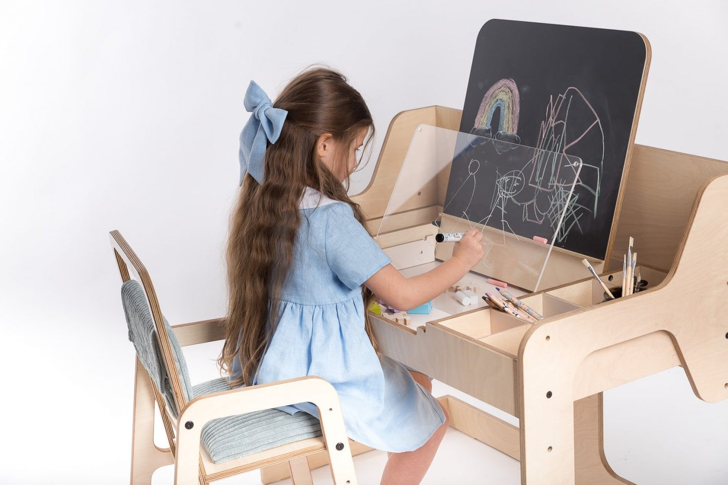 Girl drawing on chalkboard easel at Luula Montessori art table