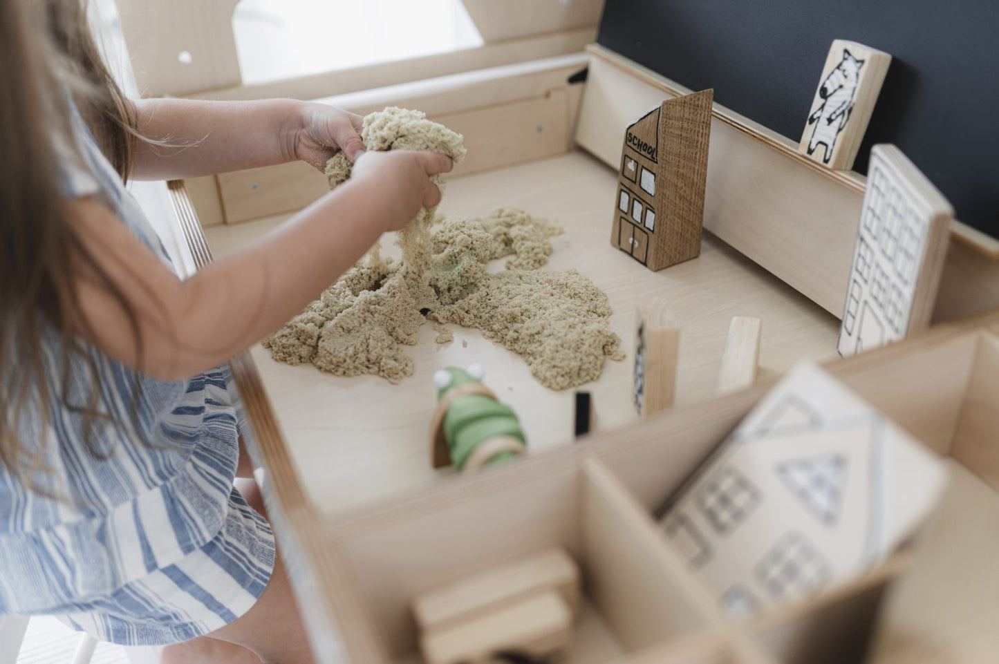 Young child playing with kinetic sand in Luula table sensory compartment