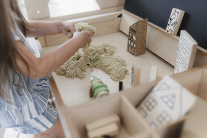 Young child playing with kinetic sand in Luula table sensory compartment