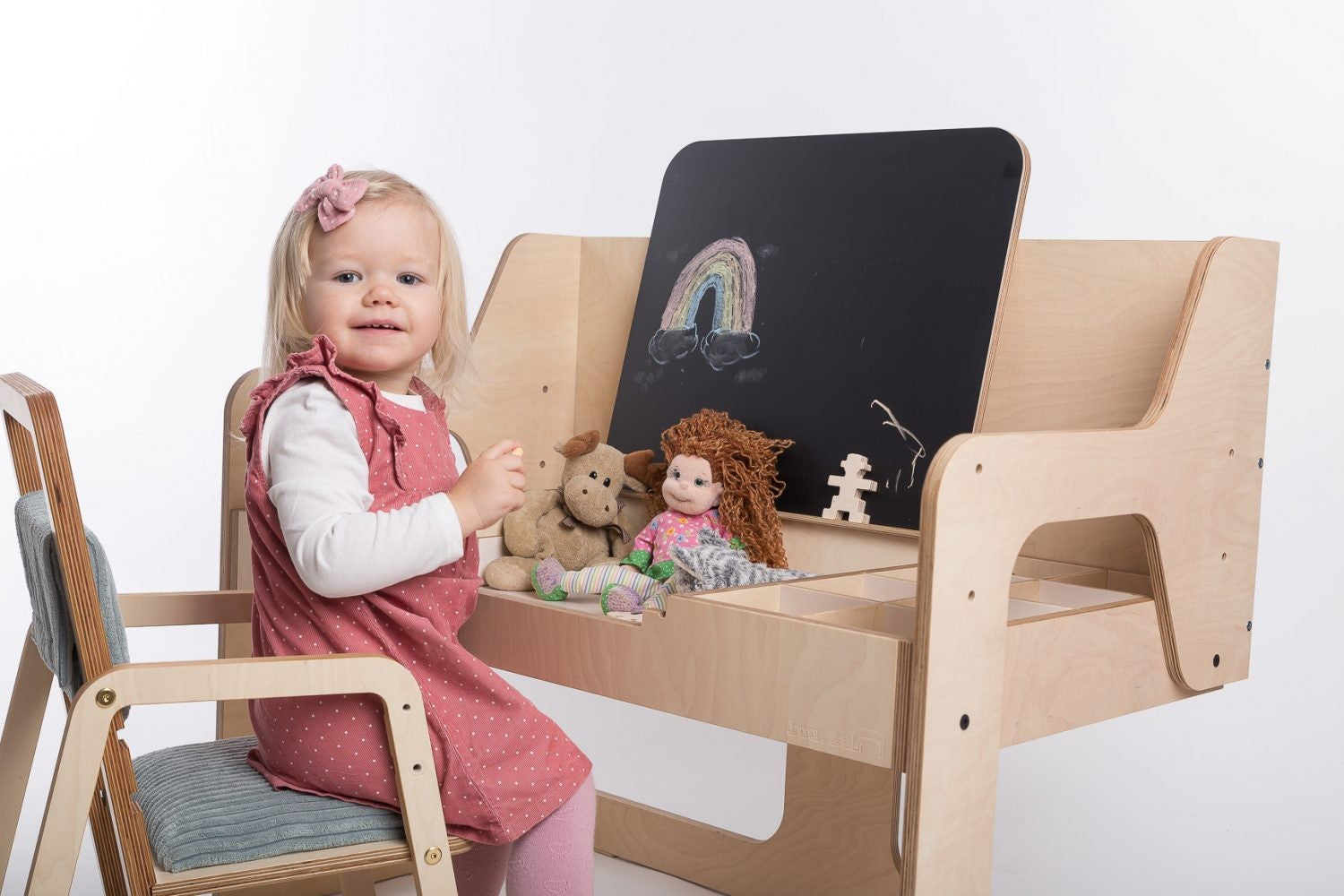 Toddler at Luula art table with toys and chalkboard for creative play
