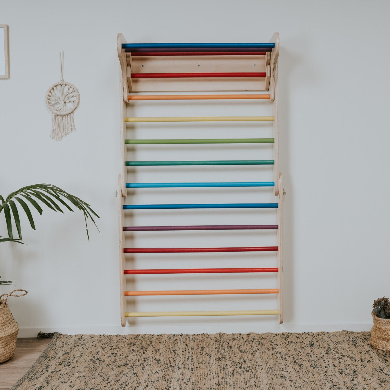 Rainbow Swedish wall climbing toy with multicolored horizontal bars mounted on white wall