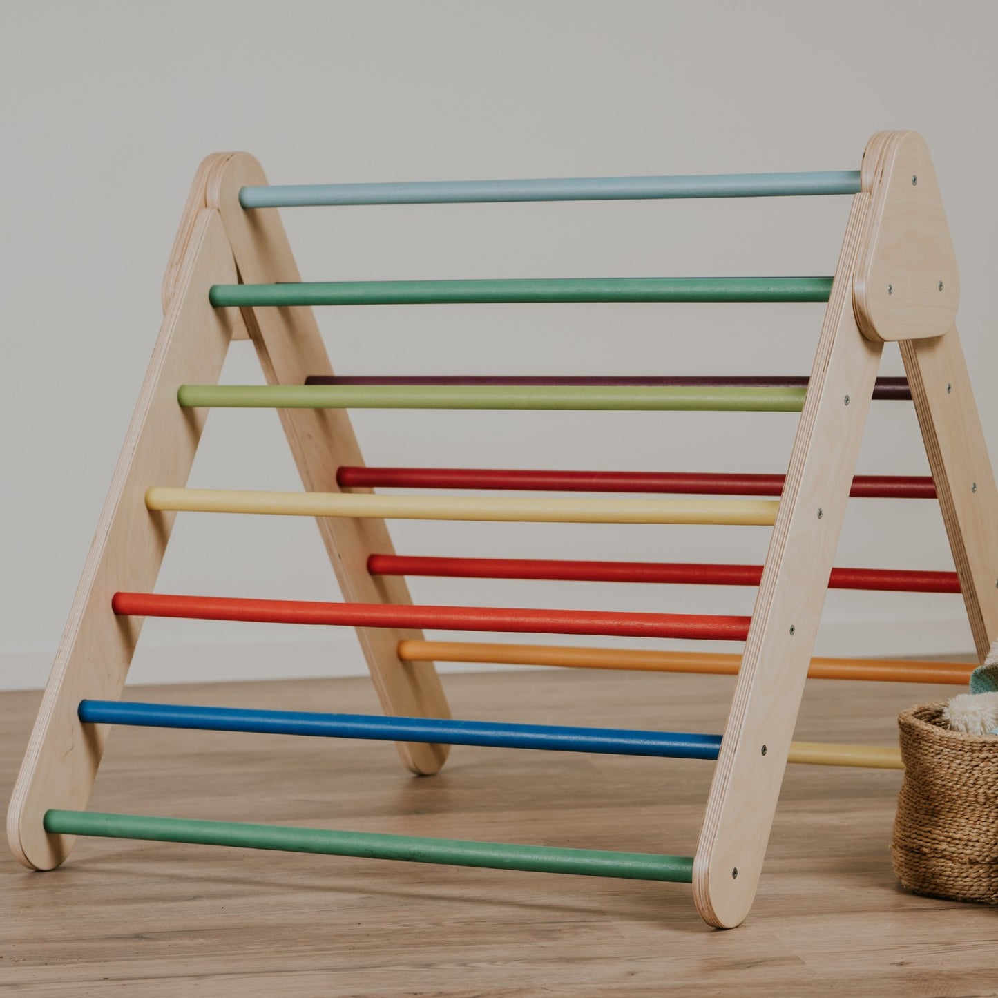 leg&go rainbow Pikler Triangle with multi-colored bars, front view on wooden floor