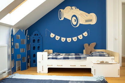 Wooden retro car wall decoration mounted on blue bedroom wall above white bed