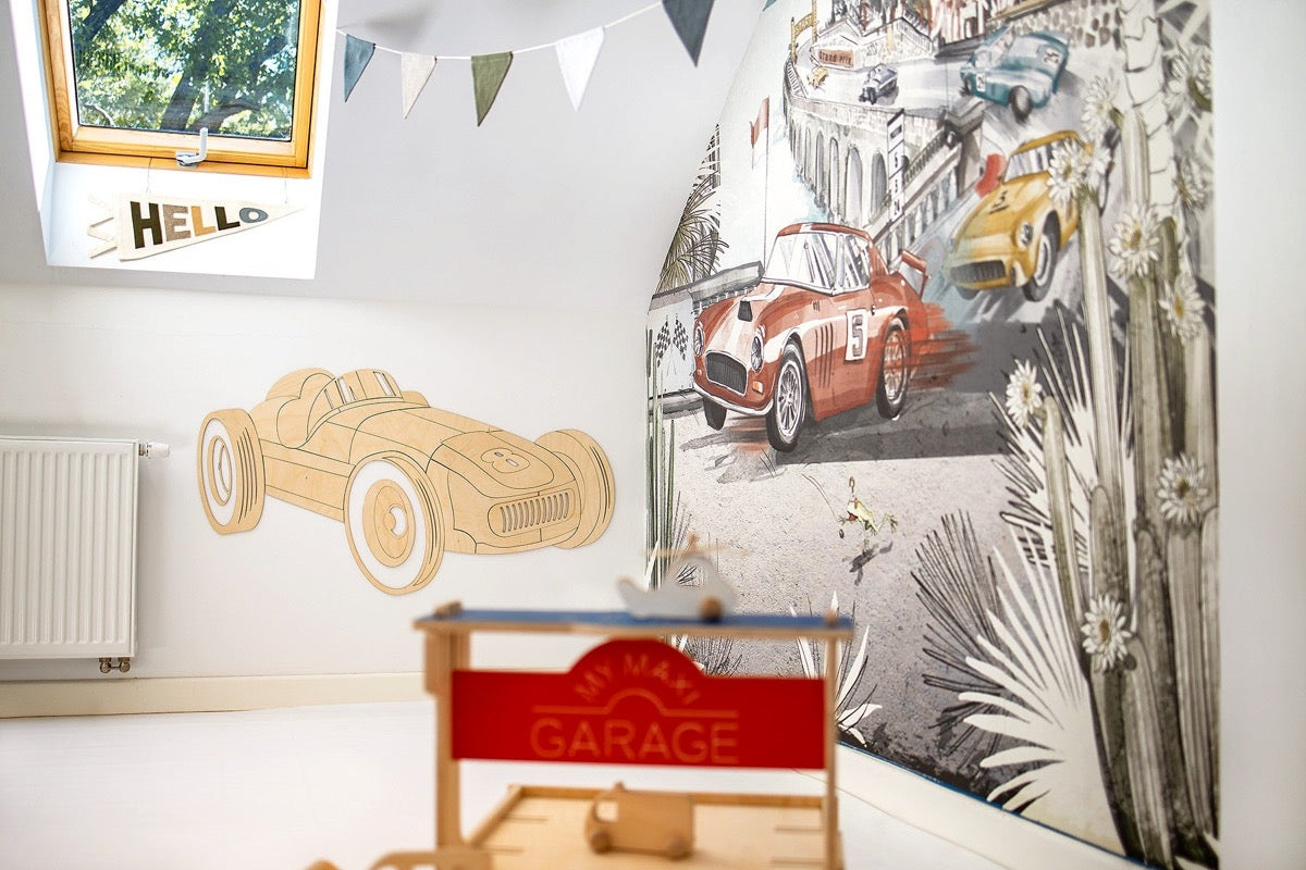 Unassembled wooden car decoration pieces next to completed wooden garage and toy track