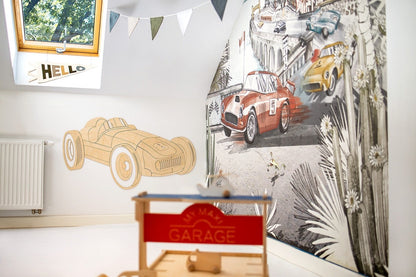 Unassembled wooden car decoration pieces next to completed wooden garage and toy track