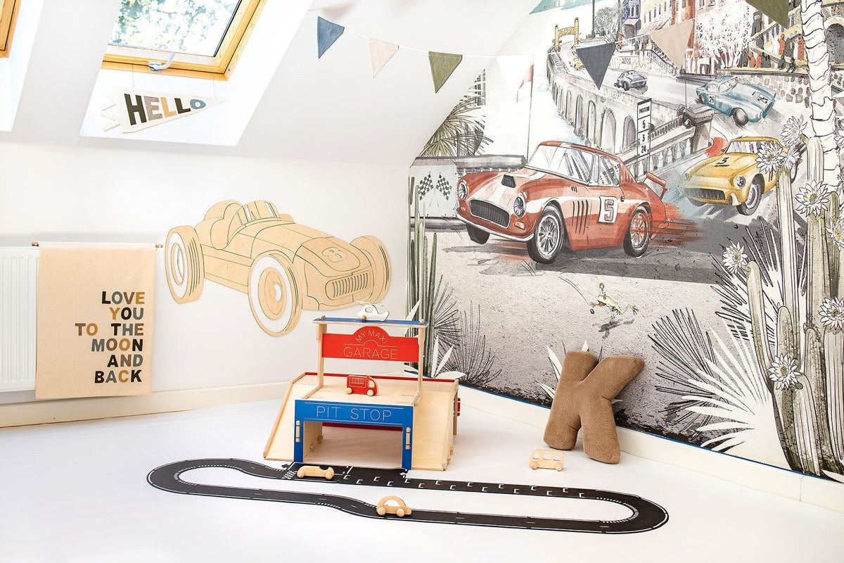 Assembled wooden racing car decoration mounted on wall above toy garage and race track