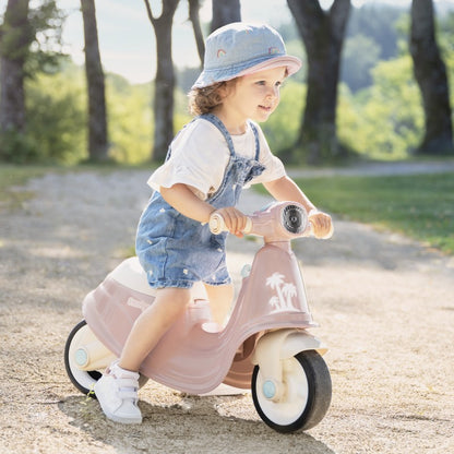 Child riding pink retro scooter in outdoor park setting