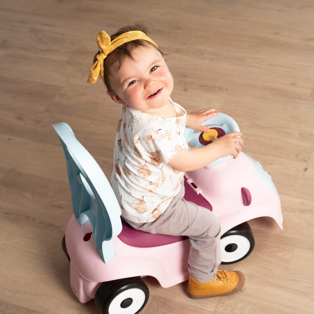 Baby sitting on pink Maestro 3in1 ride-on toy with steering wheel and canopy removed