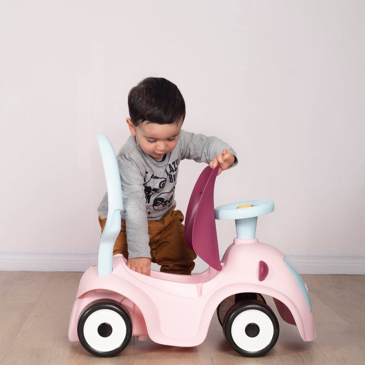 Young child using push handle on Maestro 3in1 pink ride-on for independent scooting