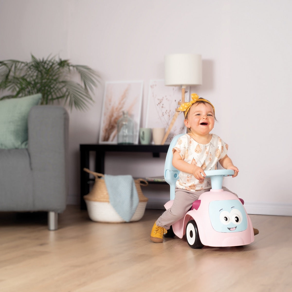 Baby playing with Maestro 3in1 pink ride-on in home setting with modern furniture