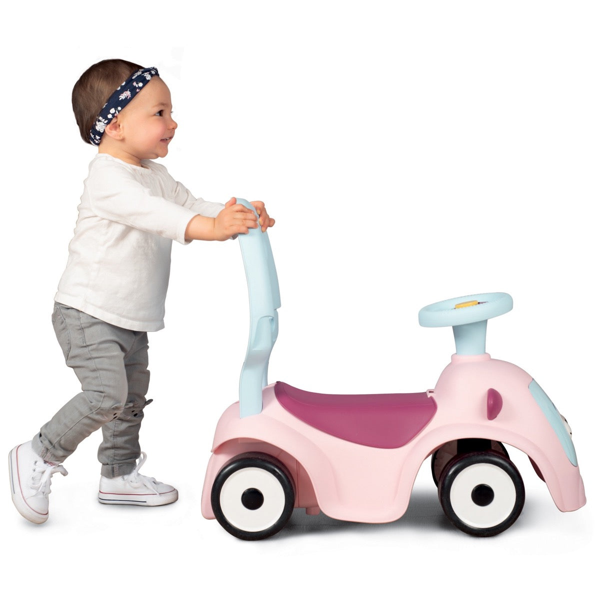 Toddler using push-along handle to move pink Maestro 3in1 ride-on forward