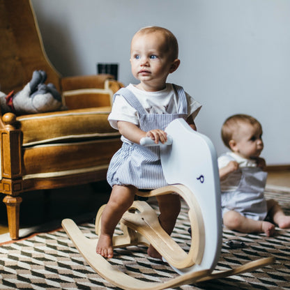 Toddler sitting on wooden rocking elephant balance bike add-on in living room