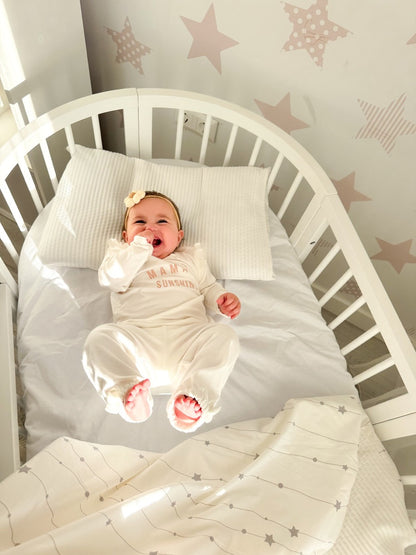 Newborn sleeping peacefully in round wooden crib with white bedding