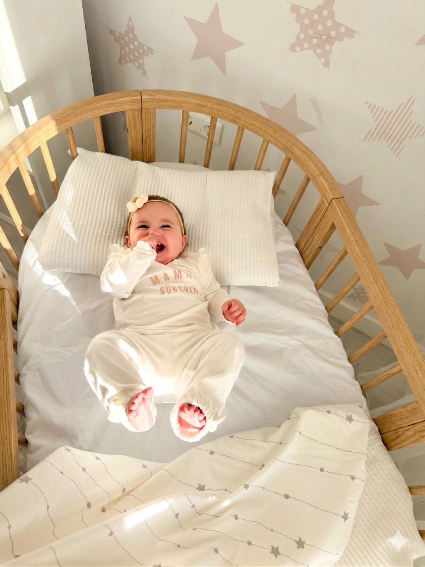 Overhead view of sleeping newborn in round crib with star pattern bedding