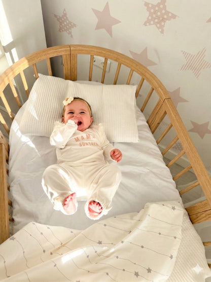 Overhead view of sleeping newborn in round crib with star pattern bedding